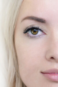 Eyelash extension procedure. Woman eye with long eyelashes. Close up. vertical photo