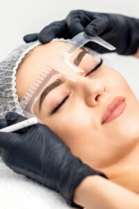 Beautician is measuring the brows with ruler before tattooing eyebrows